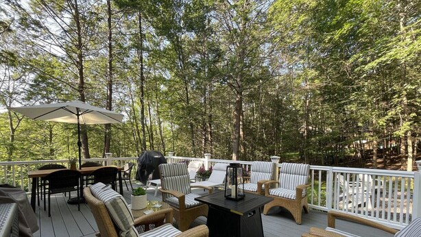 A deck with wicker furniture, a grill, and a table with a lantern. - Harbor Hideaway (York)