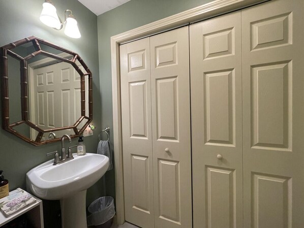 A bathroom with a white sink, a mirror with a wooden frame, and a set of beige double doors.