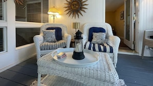 A cozy room with wicker furniture, a sun-shaped wall decoration, and a lamp. - Harbor Hideaway (York)