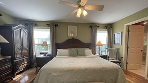 A bedroom with a large bed, a ceiling fan, a dresser, and a door. - Harbor Hideaway (York)