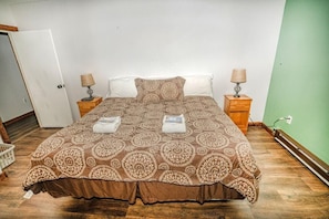 A neatly made bed with a patterned bedspread, two pillows, and two bedside lamps. - Gateway Condo A25 (Rutland)