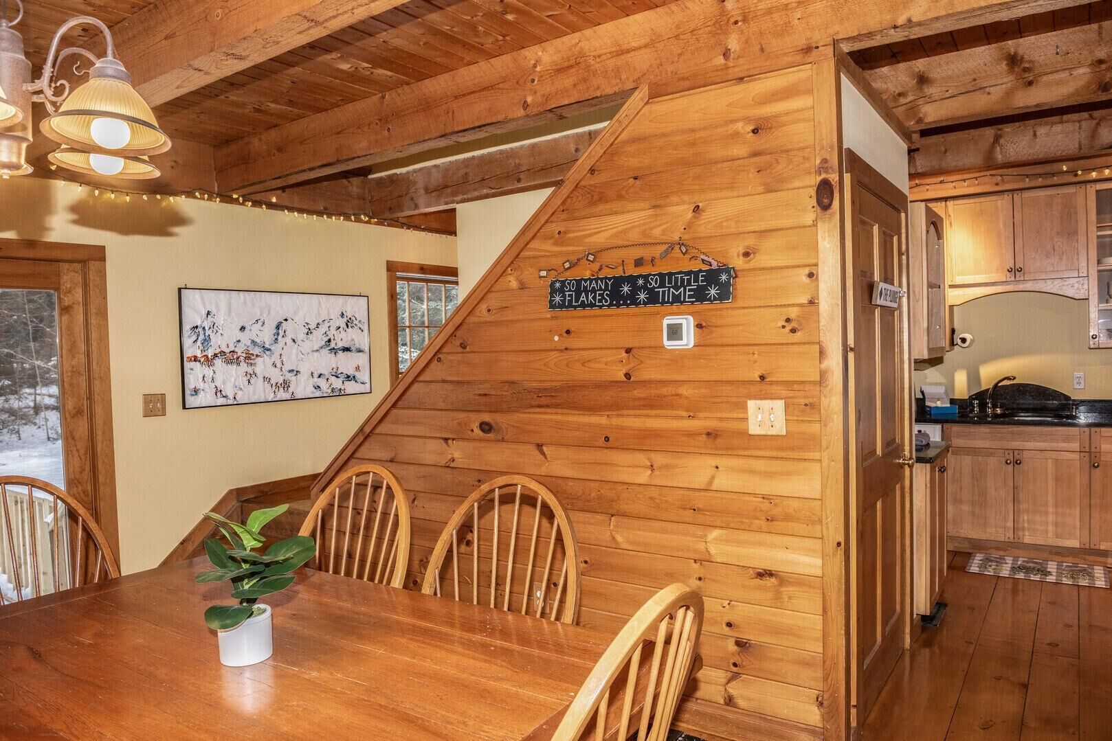 A wooden dining area with a table, chairs, and a hanging sign.