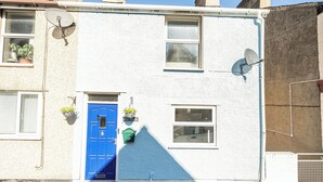 A building with a blue door, satellite dishes, and potted plants. - Stunning Sea View Blue Haven in Penmaenmawr (Penmaenmawr)