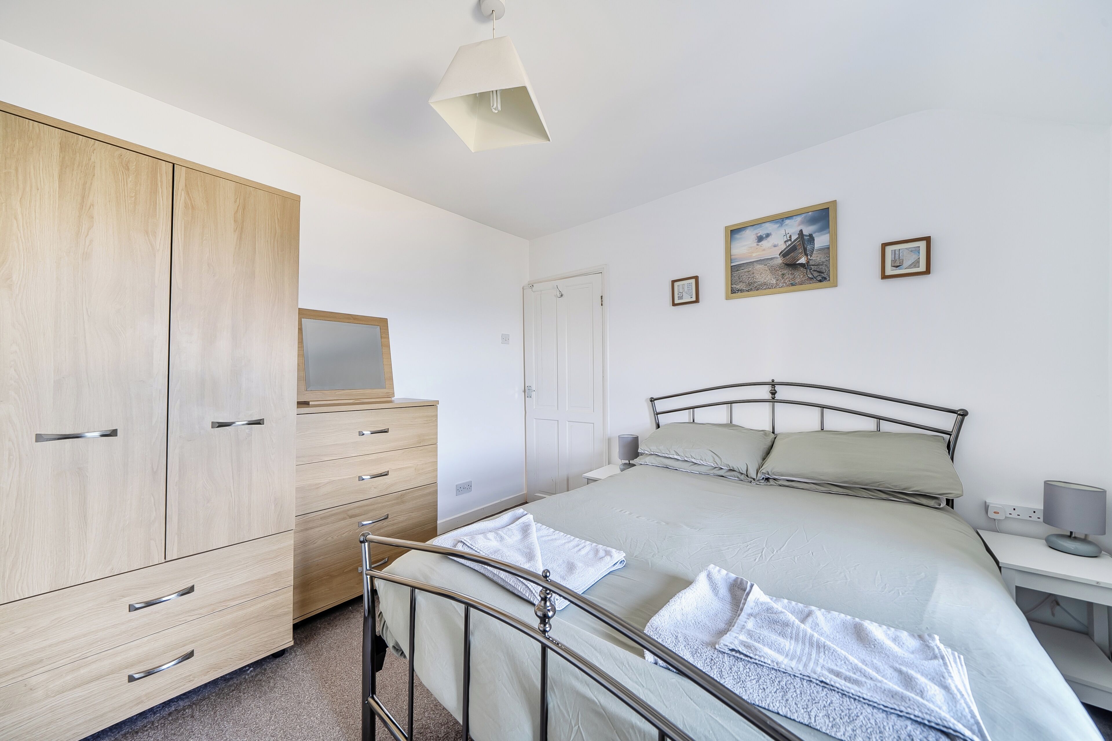 A bedroom with a bed, a wardrobe, a bedside table, and a nightstand.