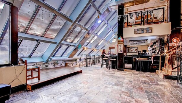 A spacious interior with a high ceiling and skylights, a bar area, and seating arrangements. - Mt Green 1-b01 (Killington)