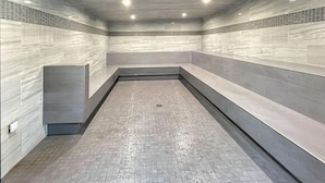 A modern, enclosed pool area with a tiled floor and walls, recessed lighting, and a bench along one side. - Mt Green 1-b01 (Killington)