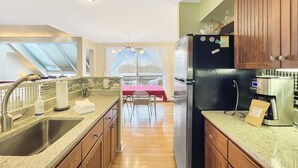 Eine moderne Küche mit einem Edelstahlkühlschrank, einer Kaffeemaschine und einem Essbereich mit Tisch und Stühlen.