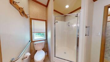 Un baño con inodoro, ducha y ventana con persianas.