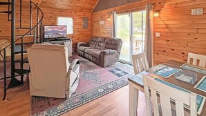 A cozy cabin interior with a wooden interior, a sofa, a dining table, and a TV. - Beach Daze Cottage (York Beach)