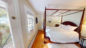 A four-poster bed in a room with a large window, a radiator, and a small table with a lamp. - Plymouth Ski Farm (Bridgewater Corners)