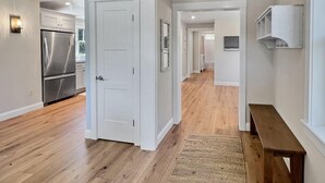 A spacious hallway with wooden flooring, white walls, and a built-in bench. - Long Sands Home (York)