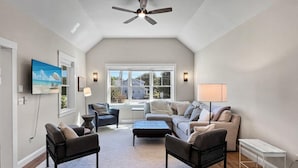A spacious living room with a high ceiling, a large window, and a ceiling fan. - Long Sands Home (York)