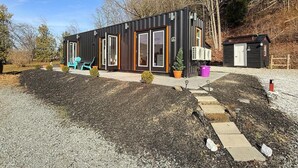 A modern, single-story building with a black exterior and large windows. - Zen Box Farm (Bomoseen)