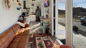 A cozy interior with a sofa, a dining area, and a kitchen. - Zen Box Farm (Bomoseen)