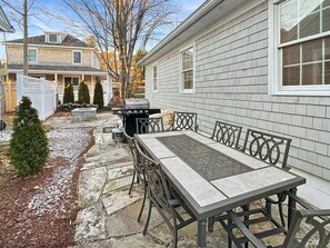 A patio with a stone table and chairs, a grill, and a small tree. - Lion's Tower (Ogunquit)