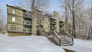 A multi-story building with balconies, a staircase, and a snow-covered ground. - Gateway Condo A10 (Rutland)