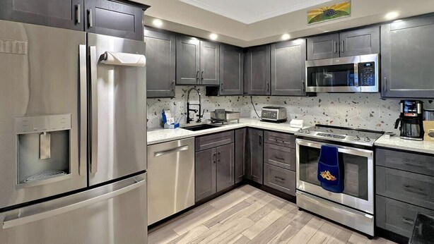 A modern kitchen with stainless steel appliances, a water dispenser, a microwave, and a coffee maker. - Gateway Condo A10 (Rutland)