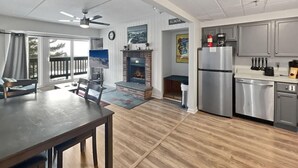 A spacious living room with a fireplace, a dining area with a table and chairs, a kitchen with modern appliances, and a balcony with a view. - Mt Green 2-d07 (Killington)