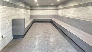 A modern, enclosed pool area with a tiled floor and walls, recessed lighting, and a bench along one side. - Mt Green 2-d07 (Killington)
