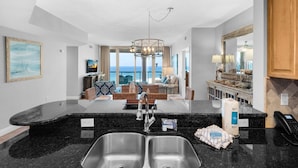 A modern kitchen with a large island, double sinks, and a view to the living area. - Portofino Island Resort 1-1402 (Pensacola Beach)