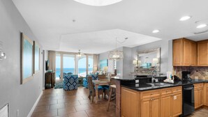 A spacious kitchen with a large island, wooden cabinets, and a view to the outside. - Portofino Island Resort 1-1402 (Pensacola Beach)