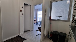 A hallway with a wooden floor, a black rug, and a door leading to a balcony. There are star decorations on the wall and a window with a view of the outside. - Beautiful renovated apartment in the heart of Concarneau - Private parking - WIFI (Concarneau)