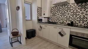 A modern kitchen with white cabinets, a microwave, a sink, and a patterned backsplash. - Beautiful renovated apartment in the heart of Concarneau - Private parking - WIFI (Concarneau)