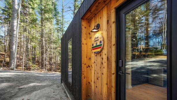 Una cabana de fusta amb una porta de vidre i un rètol que indica que és un campament.