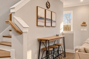 A staircase with wooden steps and white walls, a wooden bar table with stools, and a window with blinds. - NEW! Lakeside Blues: Rooftop / Marina / Family Fun (Nashville)