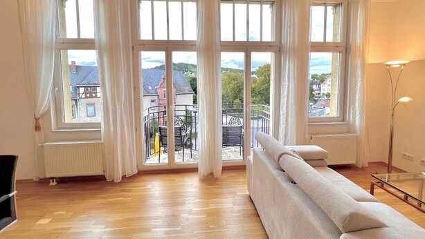 Un salón amplio con ventanas grandes, un sofá y un radiador.
