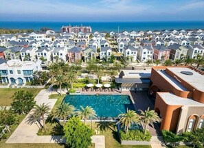 Zona residencial com piscina, palmeiras e casas.