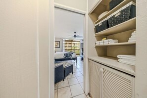 A hotel room with a bed, a seating area with a table and chairs, a balcony with a view, and a storage area with towels.