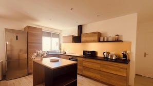 Une cuisine moderne dotée d’un îlot central, de meubles en bois et d’un four à micro-ondes encastré.