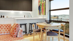 A modern kitchen with dark cabinets, a white countertop, and a large window offering a view of the city. - Gorgeous Home with Catalina Bay Views and Carpark (Auckland West)