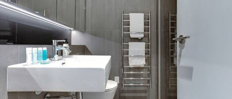 A modern bathroom with a white sink, mirror, and towel rack.
