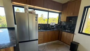 Una cocina moderna con suelo de mármol, armarios de madera y un refrigerador de acero inoxidable.