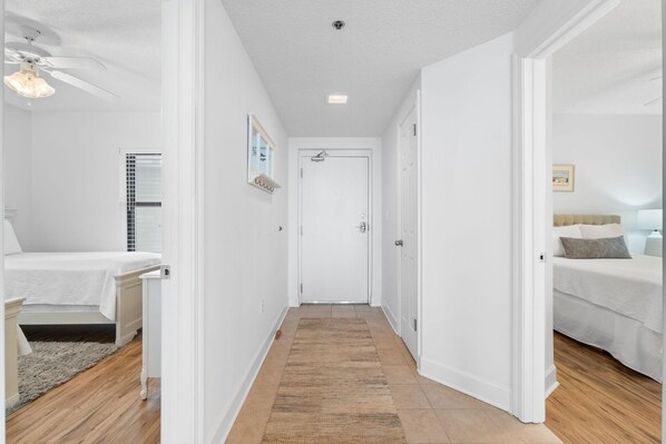 A narrow hallway with a wooden floor, white walls, and a white door at the end. - Phoenix Viii 1503 (Orange Beach)