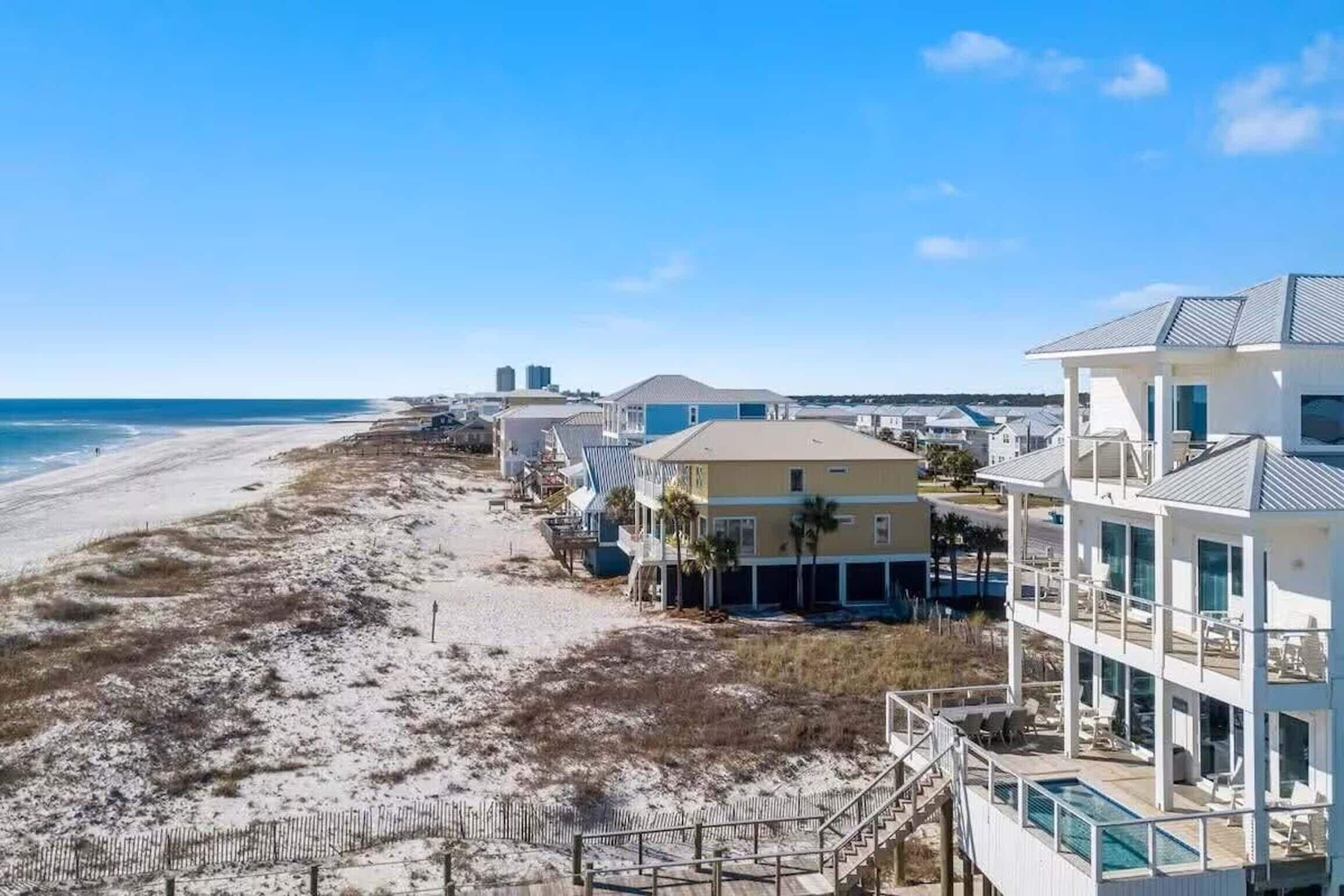 A beachfront property with a pool, multiple buildings, and a sandy beach.