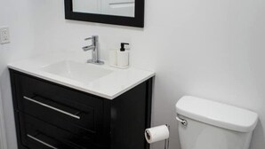 Ein Badezimmer mit einem weißen Waschbecken, einem schwarzen Schrank und einer weißen Toilette.