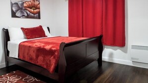 Ein Schlafzimmer mit einem dunklen hölzernen Bett, roten Vorhängen und einem floralen Gemälde an der Wand.