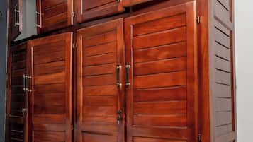A bedroom with a large wardrobe, a bed, and a small window.