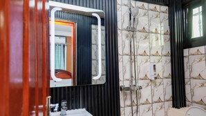 A bathroom with a sink, mirror, and shower. - T-Square Residence Makepe (Douala)