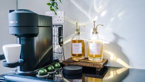 Eine Kaffeemaschine, zwei Kaffeebottel und ein kleiner Topf auf einer Holztablett.