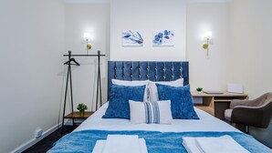 Ein ordentlich eingerichtetes Hotelzimmer mit einem Bett, einem Schreibtisch, einem Stuhl und zwei Wandleuchten.