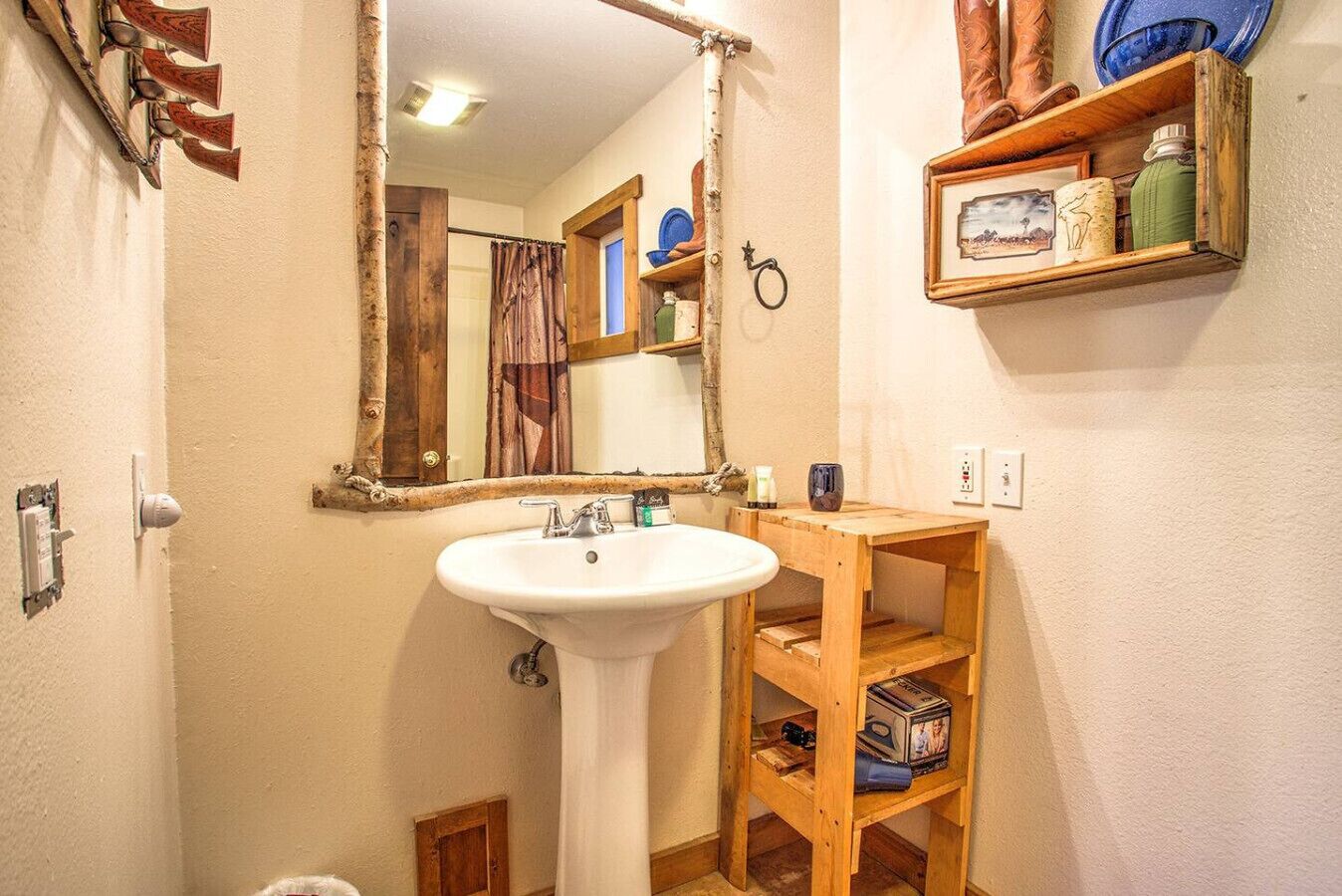 A bathroom with a white sink, wooden shelves, a mirror, and a shower curtain.