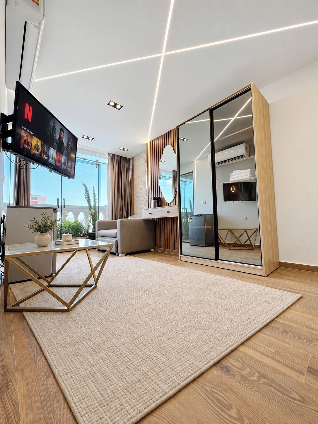 Una sala de estar moderna con un televisor de pantalla plana, un separador de vidrio y vistas al exterior.