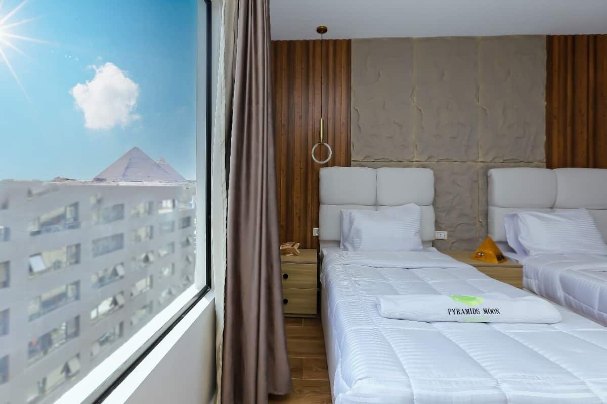 Habitación de hotel con dos camas, vista a las pirámides y una pared de madera.