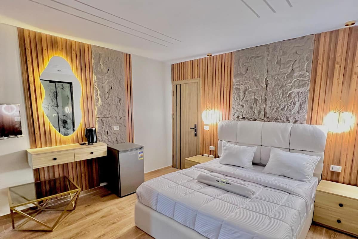 Un dormitorio moderno con una cama grande, paneles de madera, un escritorio empotrado y una mesa de centro de vidrio.