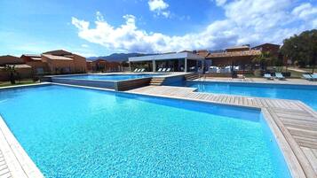 Une grande piscine extérieure dotée de terrasses en bois et de chaises longues.