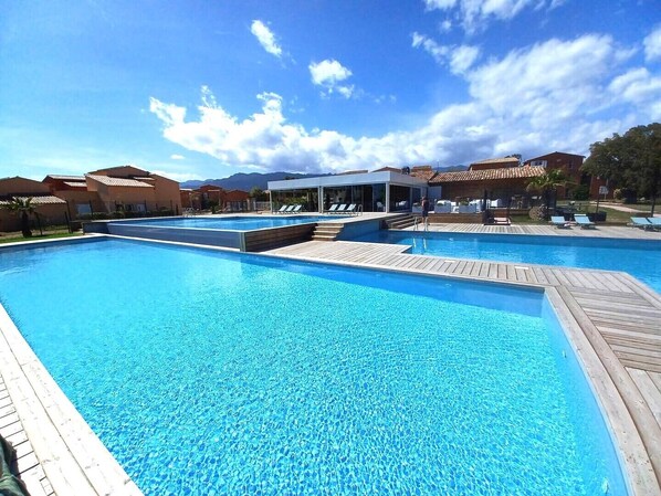 A large outdoor swimming pool with wooden deck areas and lounge chairs.